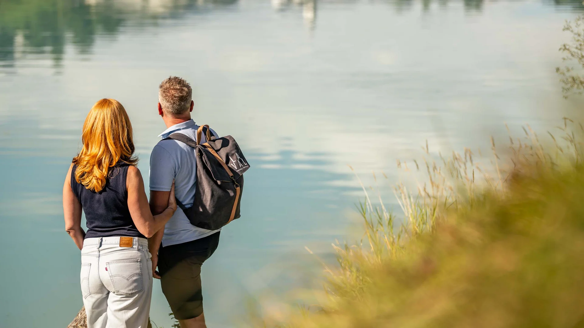 La Val Hotel & Spa: Ihr Hotel in Breil/Brigels Paar steht am Ufer und blickt auf ruhigen See mit Spiegelung
