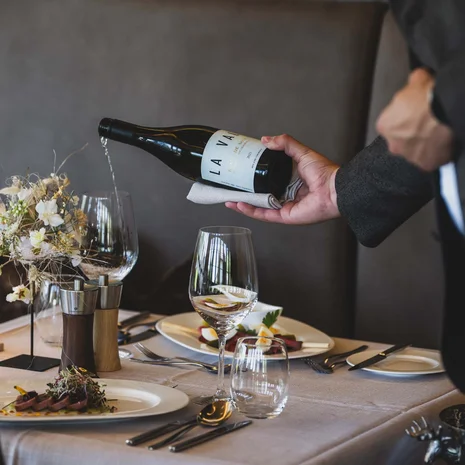 La Val Hotel & Spa: Ihr Hotel in Breil/Brigels Kellner gießt Wein in ein Glas bei einem eleganten Restaurantessen