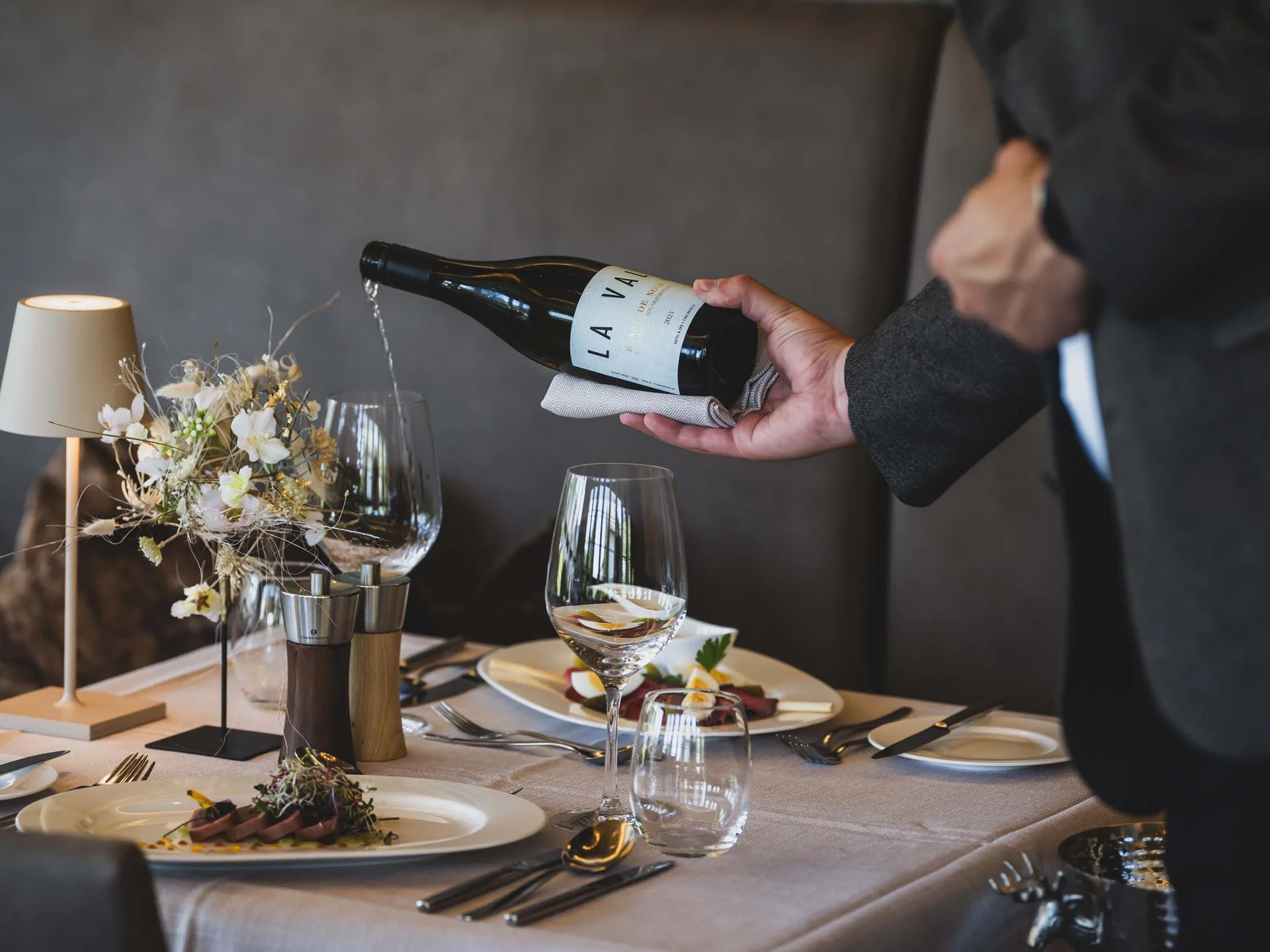La Val Hotel & Spa: Ihr Hotel in Breil/Brigels Kellner gießt Wein in ein Glas bei einem eleganten Restaurantessen
