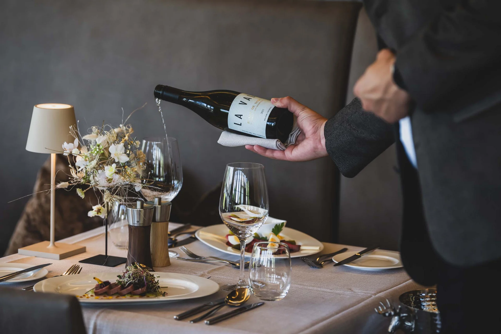 La Val Hotel & Spa: Ihr Hotel in Breil/Brigels Kellner gießt Wein in ein Glas bei einem eleganten Restaurantessen