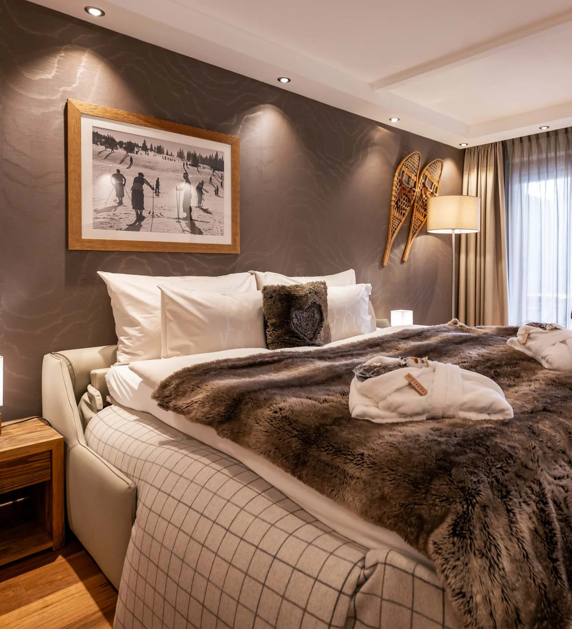 La Val Hotel & Spa: Ihr Hotel in Breil/Brigels Gemütliches Schlafzimmer mit Fellbettdecke, Schneeschuhen an der Wand und Holzboden