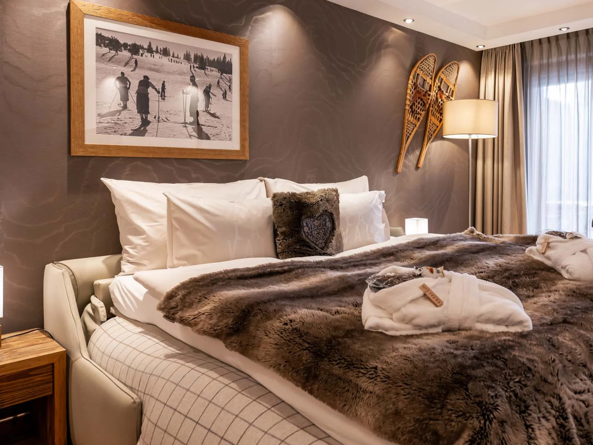 La Val Hotel & Spa: Ihr Hotel in Breil/Brigels Gemütliches Schlafzimmer mit Fellbettdecke, Schneeschuhen an der Wand und Holzboden