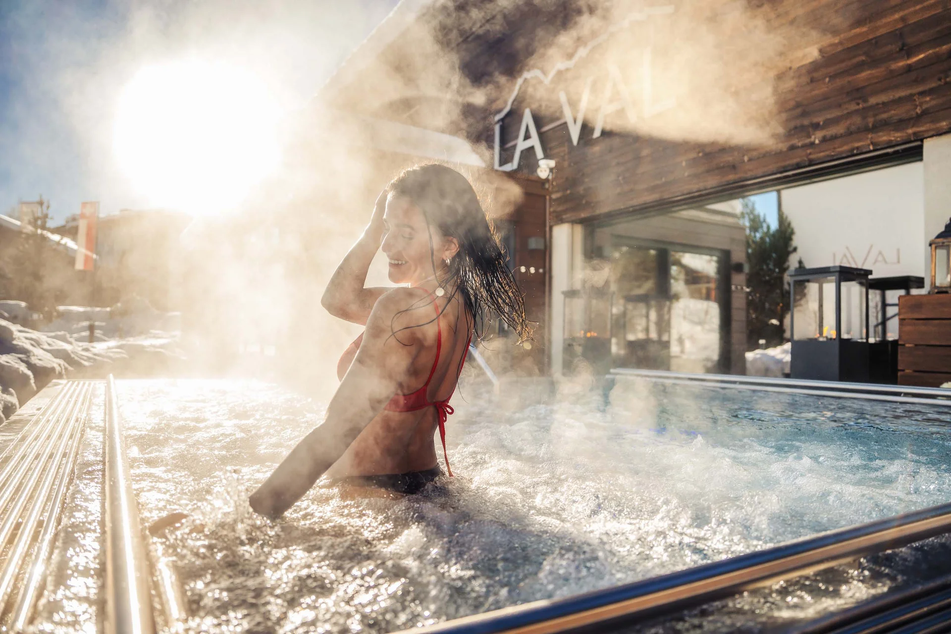 La Val Hotel & Spa: Ihr Hotel in Breil/Brigels Frau entspannt im dampfenden Außenwhirlpool bei Sonnenschein