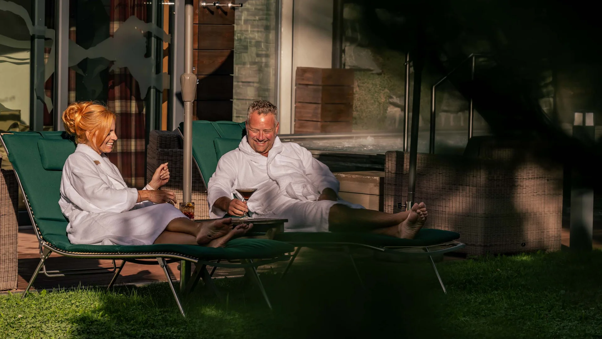 La Val Hotel & Spa: Ihr Hotel in Breil/Brigels Paar entspannt im Bademantel auf Liegestühlen mit Getränken im Freien